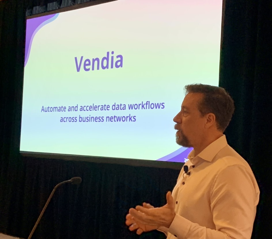 Tim Wagner gives a presentation with Vendia's logo and the value proposition projected on the screen behind him; it reads, "Automate and accelerate your data workflows across business networks"